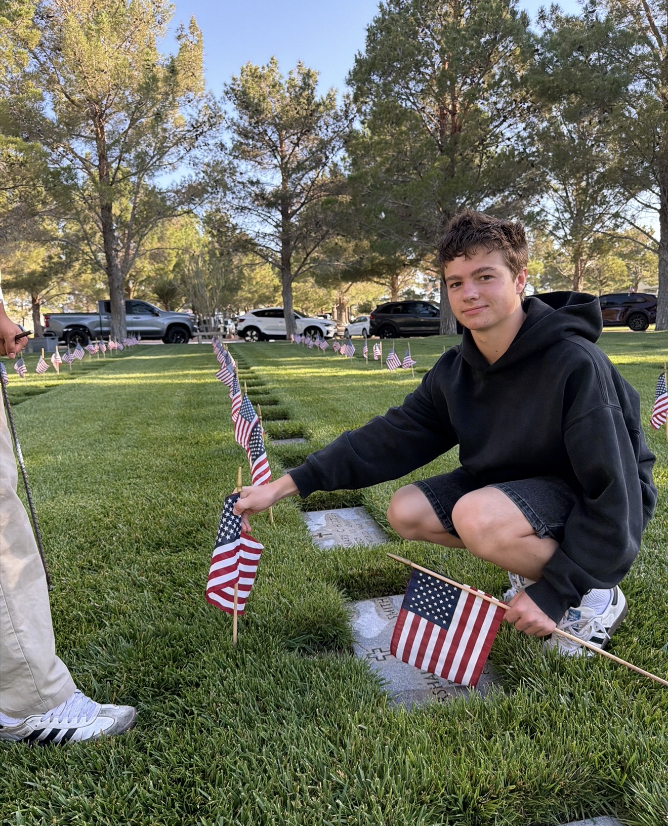 Youth volunteer placing an American flag at a veteran's memorial marker